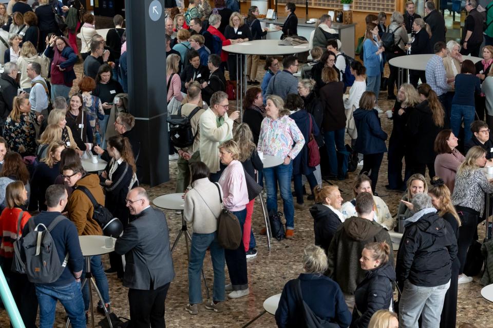 Teilnehmende des Grundschulleitungstages stehen in Gruppen zusammen und sprechen miteinander.