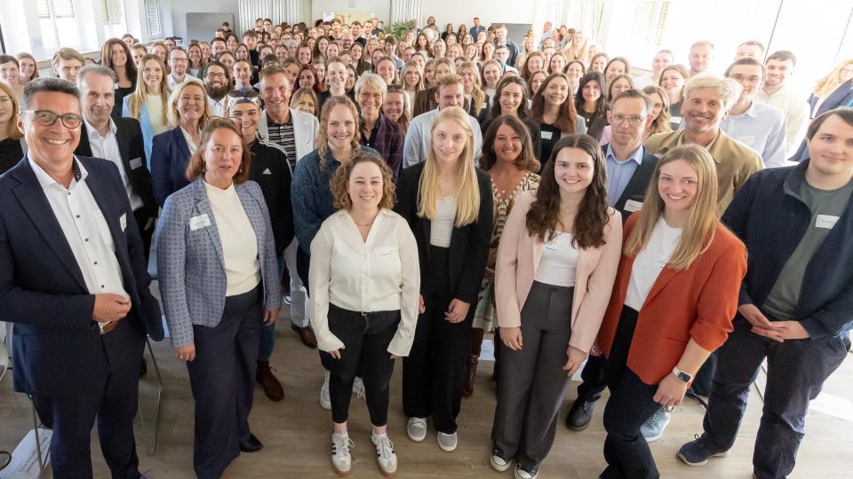 Personen stehen in einem Veranstaltungsraum für ein Gruppenbild zusammen