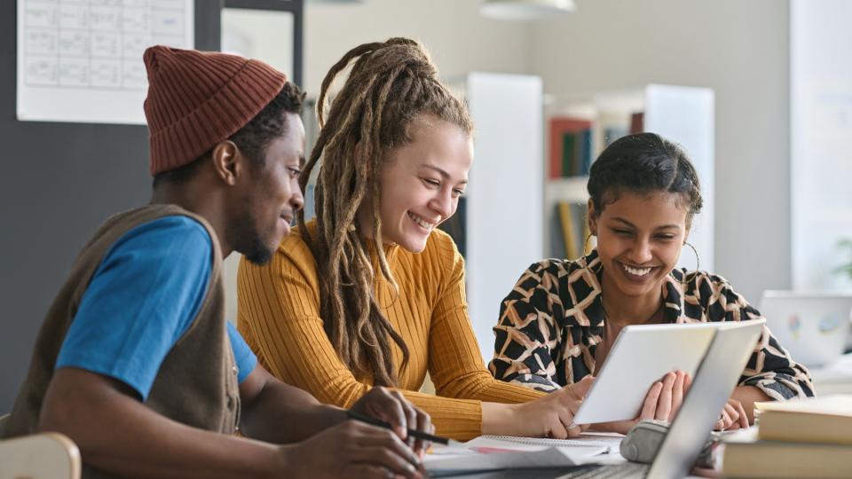 Eine junge Lehrerin arbeitet mit einer Schülerin und einem Schüler aus einer "Fit für mehr"-Klasse zusammen.