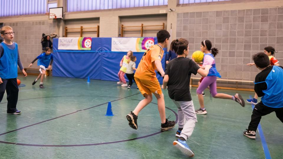 Kinder laufen in einer Turnhalle 