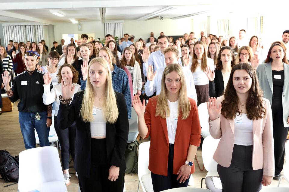 Junge Frauen und Männer stehen in einer Gruppe und haben die Hand zum Eid erhoben.