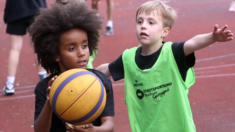 Zwei Jungen spielen Basketball.