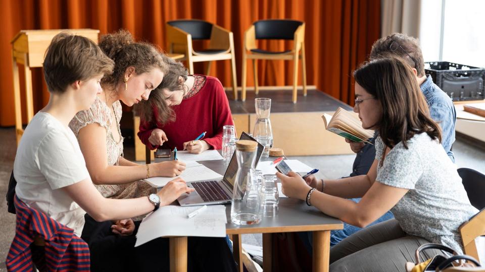 Jugendliche sitzen gemeinsam am Tisch und arbeiten an ihrer Lyrik.