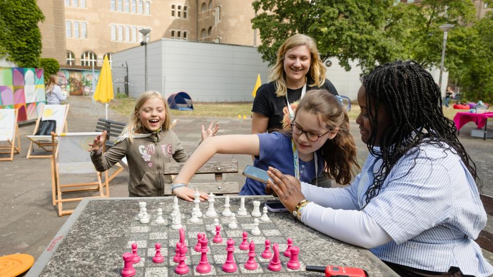 Auf einem Schulhof spielen Mädchen Schach.