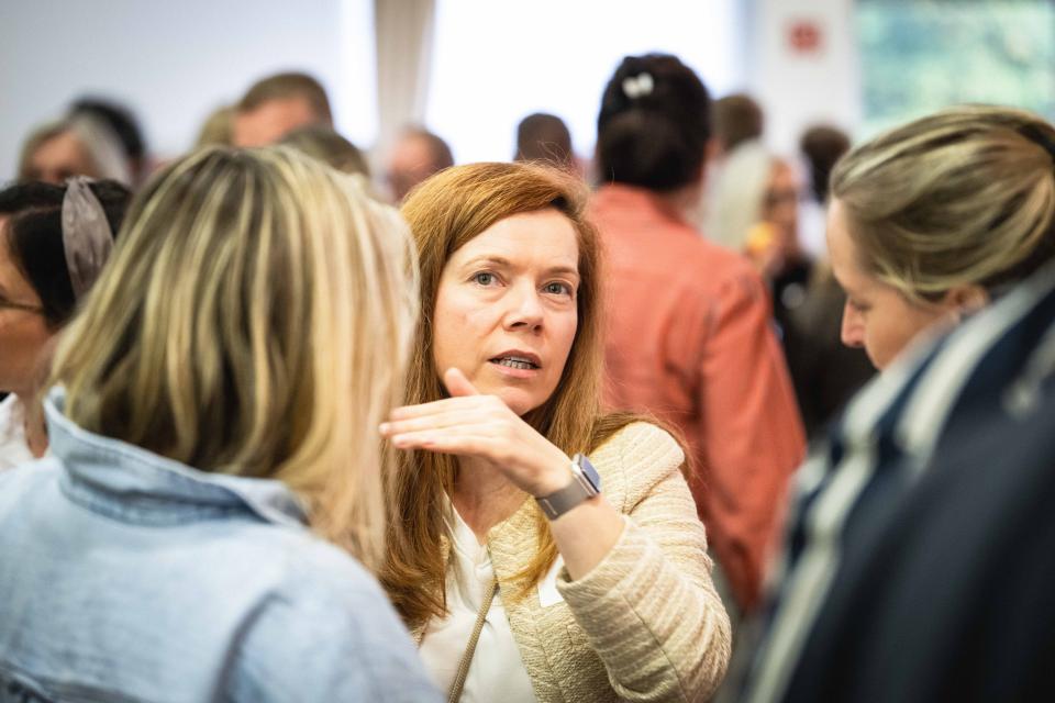 Hauptschultag 2026: Viele Personen stehen zu Gesprächen zusammen, Zoom auf eine sprechende Teilnehmerin.