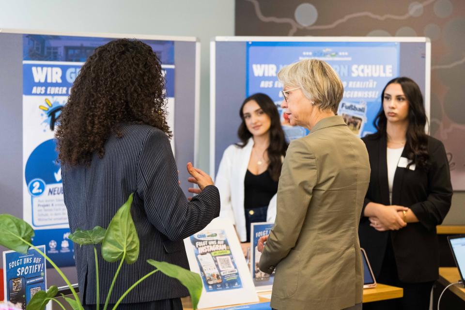 Hauptschultag 2026: Ministerin Feller besucht einen Informationsstand und spricht mit einer Teilnehmerin.