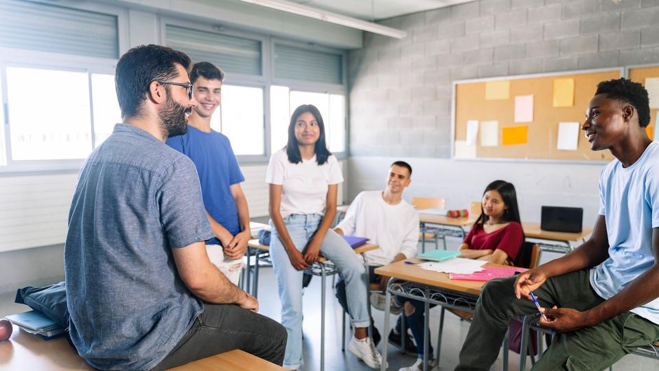 Schülerinnen und Schüler diskutieren mit einem Lehrer.