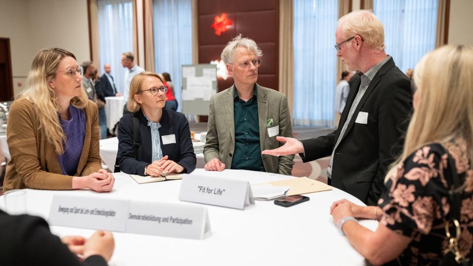Teilnehmerinnen und Teilnehmer des Stiftungstages stehen zum Gespräch zusammen.