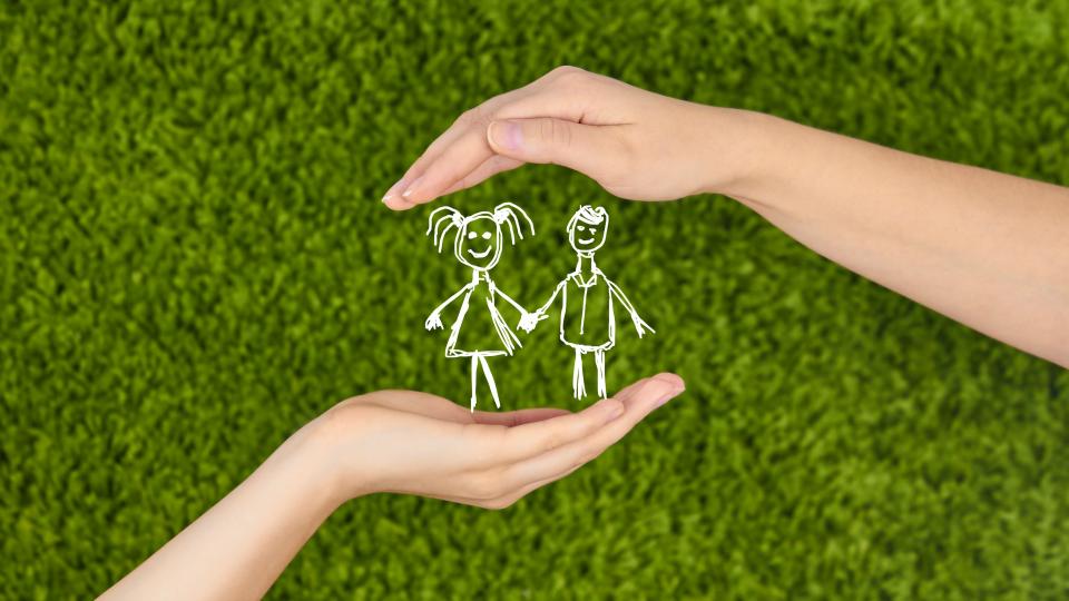 Nahaufnahme zweier Hände, die sich schützend um zwei Strichmännchen-Kinder formen. Nahaufnahme zweier Hände, die sich schützend um zwei Strichmännchen-Kinder formen.