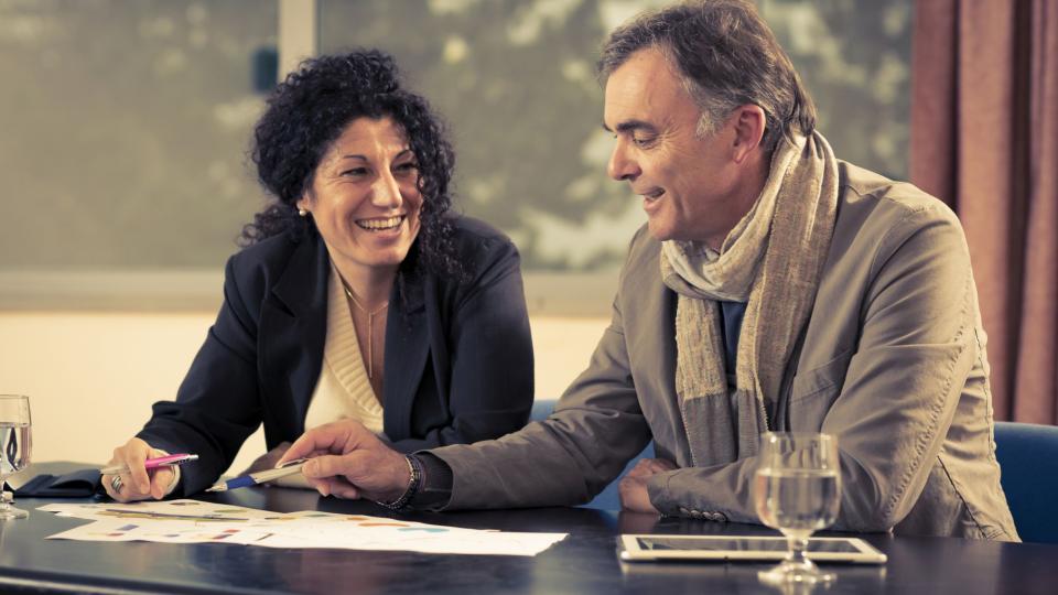 Eine Frau und ein Mann sitzen an einem Tisch und sprechen miteinander. Eine Frau und ein Mann sitzen an einem Tisch und sprechen miteinander.