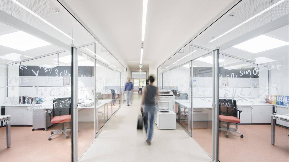 Lehrer gehen an verglasten Büros vorbei. Lehrer gehen an verglasten Büros vorbei.