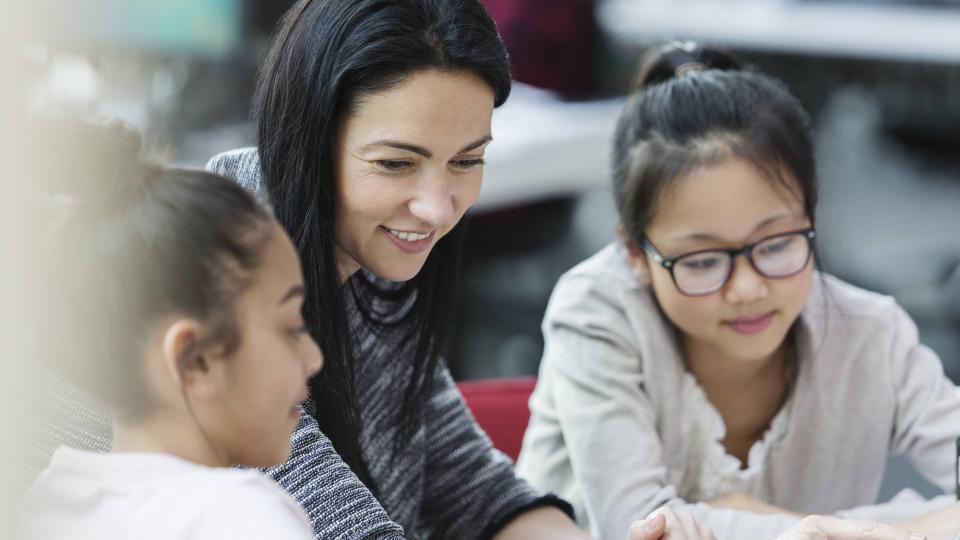 Lehrerin mit zwei Schülerinnen vor einem Computer.