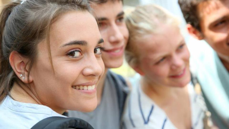 Mädchen lächelt aus einer Gruppe Schüler heraus in die Kamera. Mädchen lächelt aus einer Gruppe Schüler heraus in die Kamera.