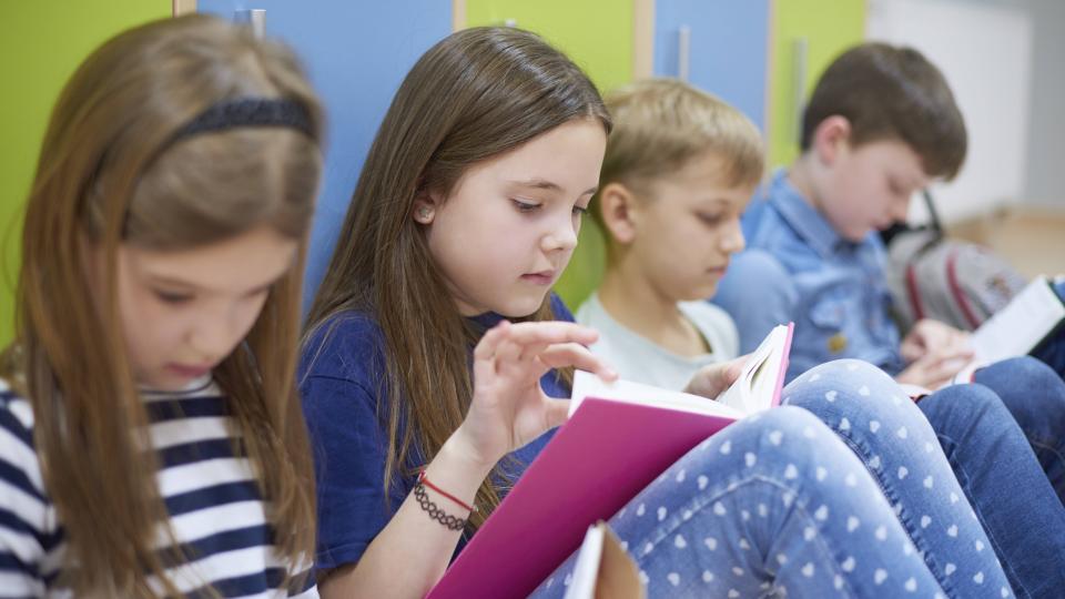 Grundschüler lernen zusammen in einem Schulflur.