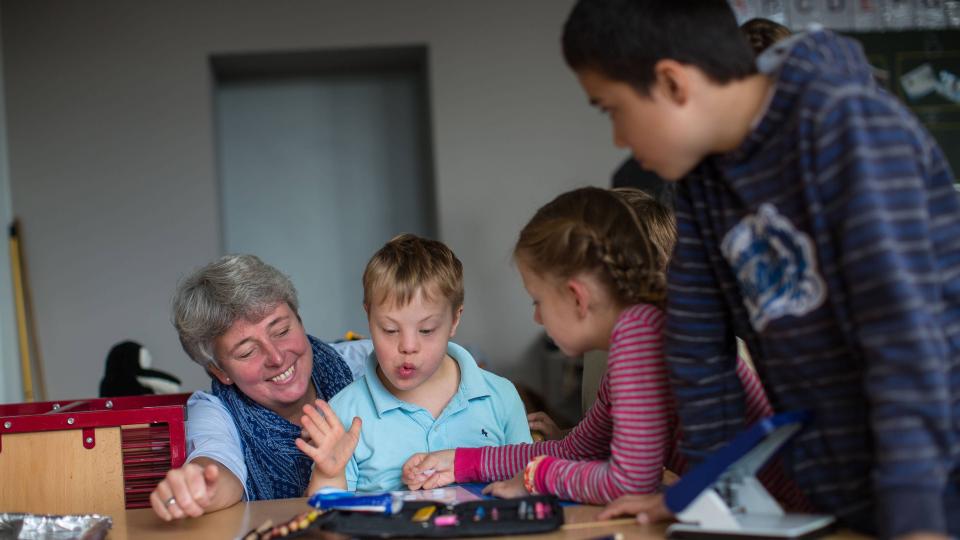 Lehrerin und Kinder mit und ohne Behinderung in Unterrichtssituation