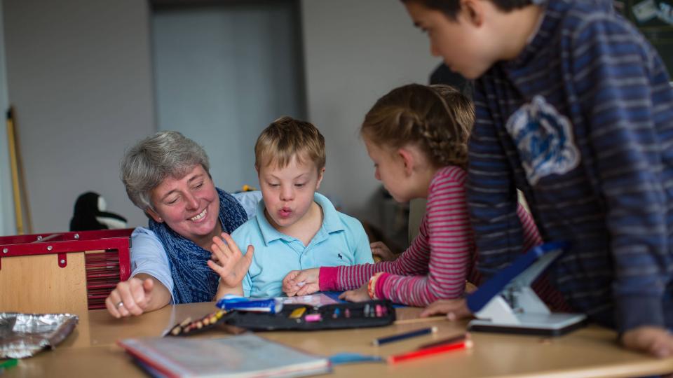 Lehrerin und Kinder mit und ohne Behinderung in Unterrichtssituation