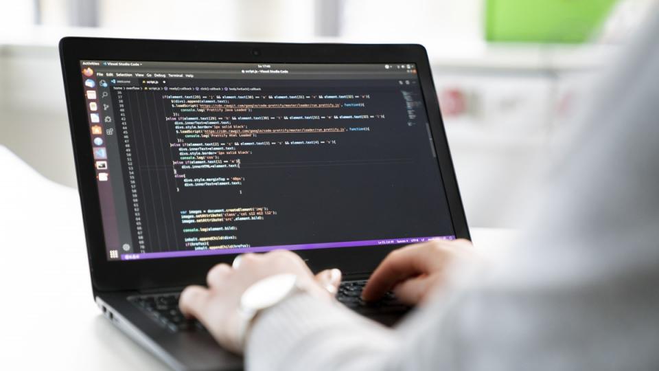 Nahaufnahme eines geöffneten Laptops, auf dem ein Computerprogramm zu sehen ist. Hände schweben über der Tastatur.