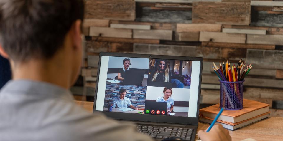Junge sitzt vor einem Laptop auf dem eine Videokonferenz läuft.