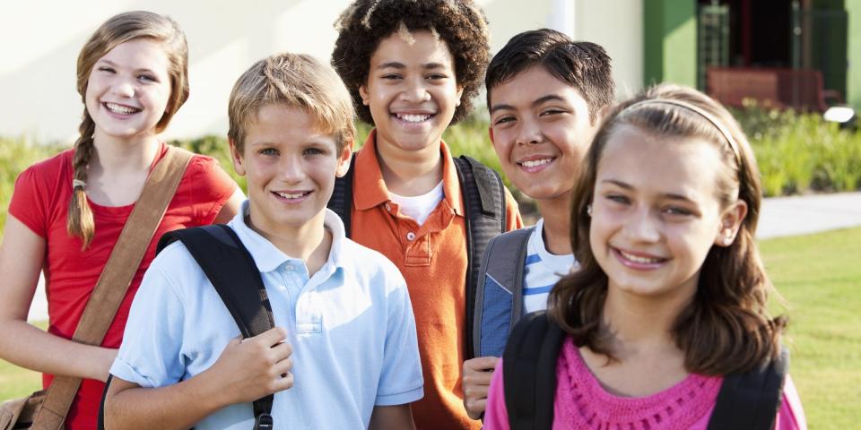 Eine Gruppe Schülerinnen und Schüler stehen auf einer Wiese vor einem Gebäude.