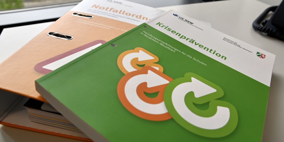 Nahaufnahme des Notfallordners, auf dem das Präventionshandbuch liegt.