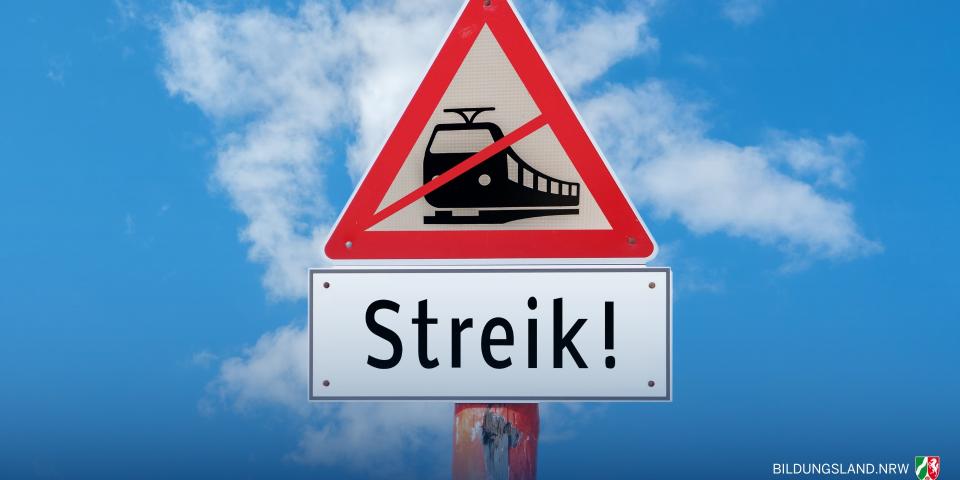 Straßenschild vor blauem Himmel mit der grafischen Darstellung eines durchgestrichenen Zuges. Darunter steht auf einem Schild "Streik!".
