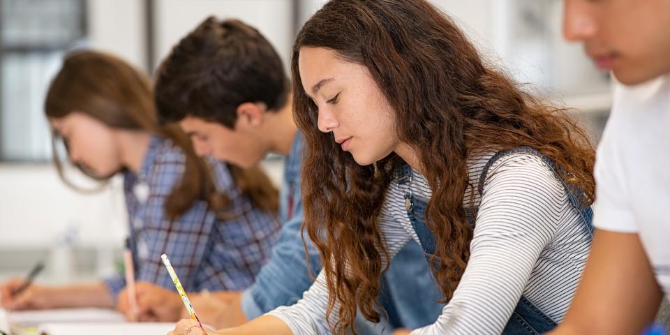 Schülerinnen und Schüler sind in eine schriftliche Prüfung vertieft.