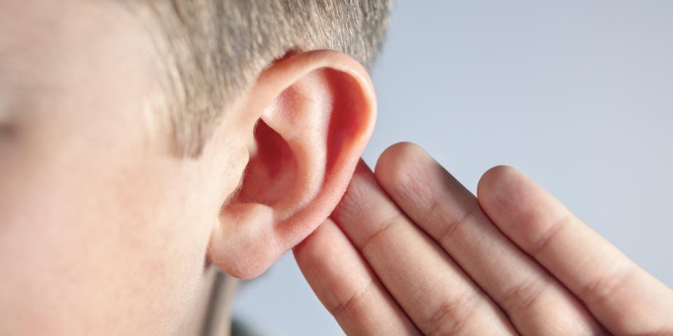 Nahaufnahme eines Kindes, das sich die Hand hinter das Ohr hält.