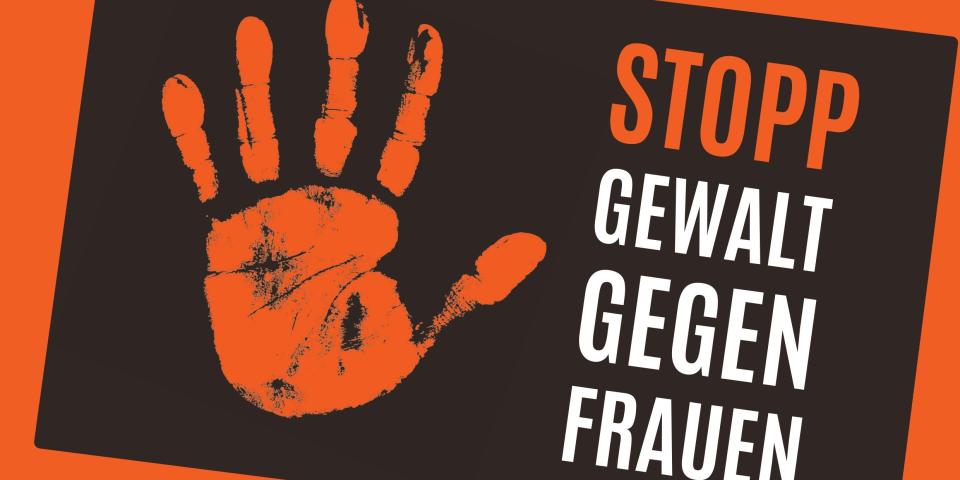 Eine Hand hält ein Plakat mit dem Aufdruck "Stopp Gewalt gegen Frauen"