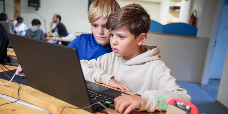 Zwei Schüler sitzen am Laptop.