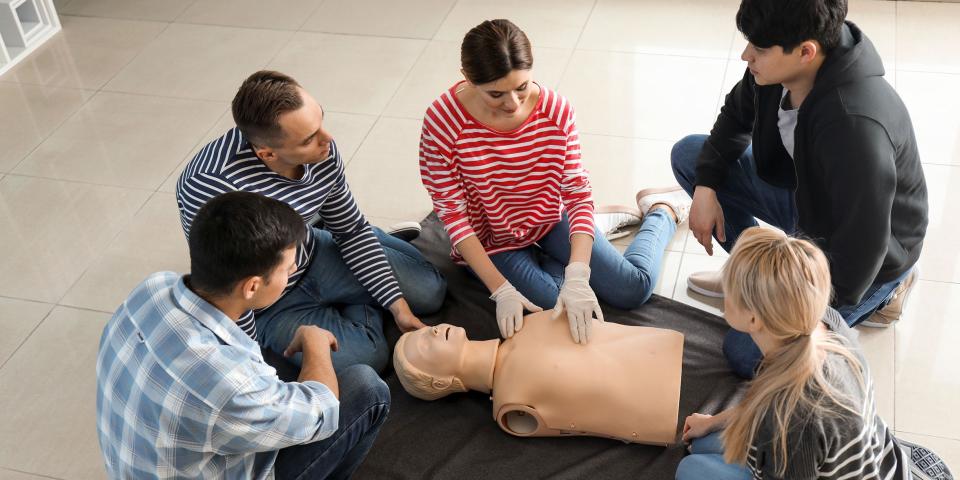 Lehrkräfte, Schülerinnen und Schüler üben die Reanimation an einem Wiederbelebungsphantom.