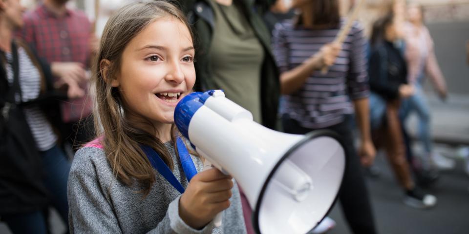 Symbolbild: Mädchen mit einem Megafon in einer Gruppe Demonstrierender.