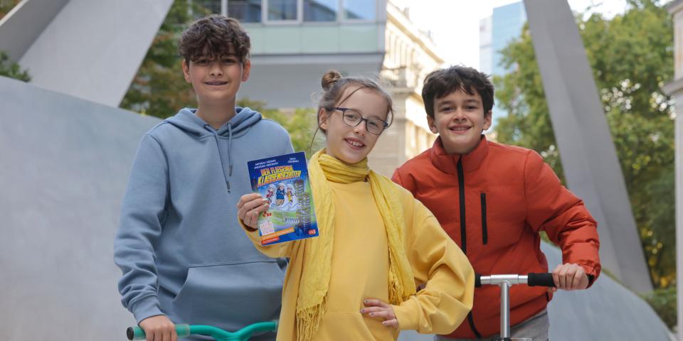 Drei Jugendliche halten das aktuelle Buch der Buch-Gutschein-Aktion 2026 in der Hand.