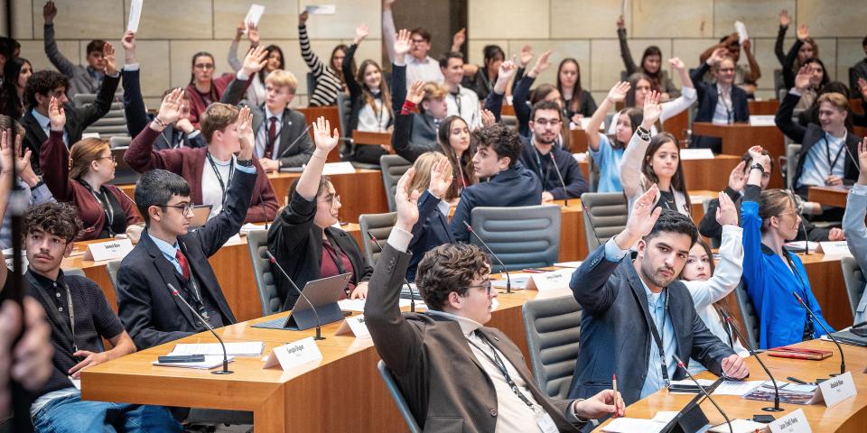 Schülerinnen und Schüler nehmen an einem Aktionstag im Landtag teil und führen eine Abstimmung im Plenarsaal durch.