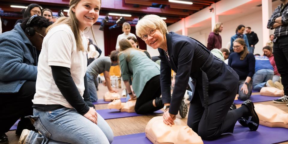 Ministerin Feller demonstriert Reanimation an einer Puppe.