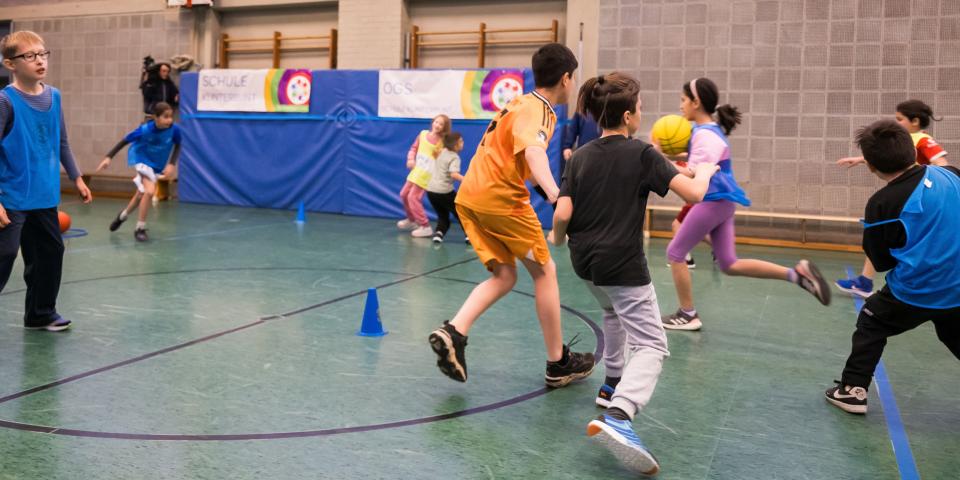 Kinder laufen in einer Turnhalle 