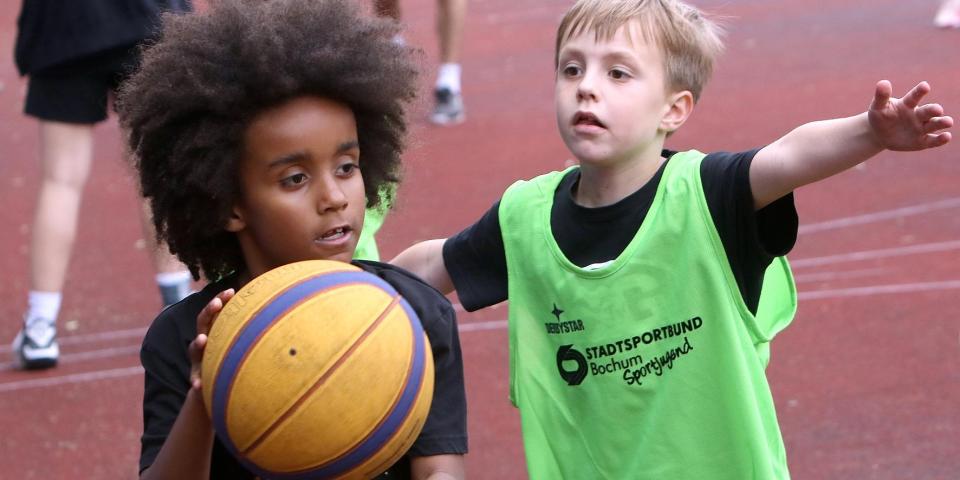 Zwei Jungen spielen Basketball.