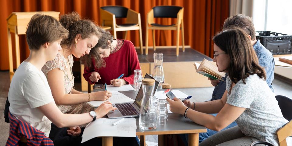 Jugendliche sitzen gemeinsam am Tisch und arbeiten an ihrer Lyrik.
