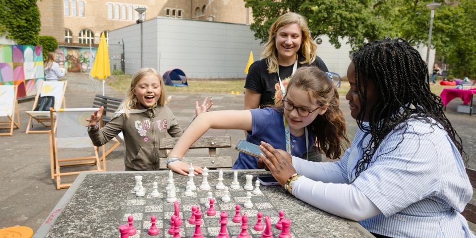 Auf einem Schulhof spielen Mädchen Schach.