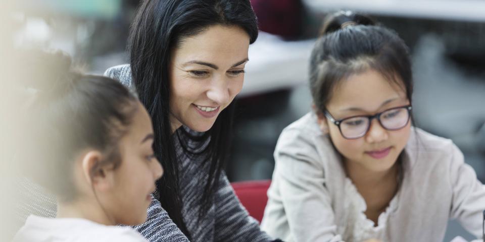 Lehrerin mit zwei Schülerinnen vor einem Computer.