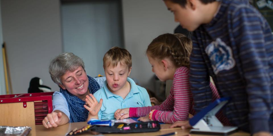 Lehrerin und Kinder mit und ohne Behinderung in Unterrichtssituation