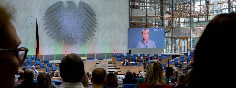 Grundschulleitertag im WCC in Bonn, auf einem großen Bildschirm erscheint das Begrüßungsvideo von Ministerin Feller (25. März 2026)