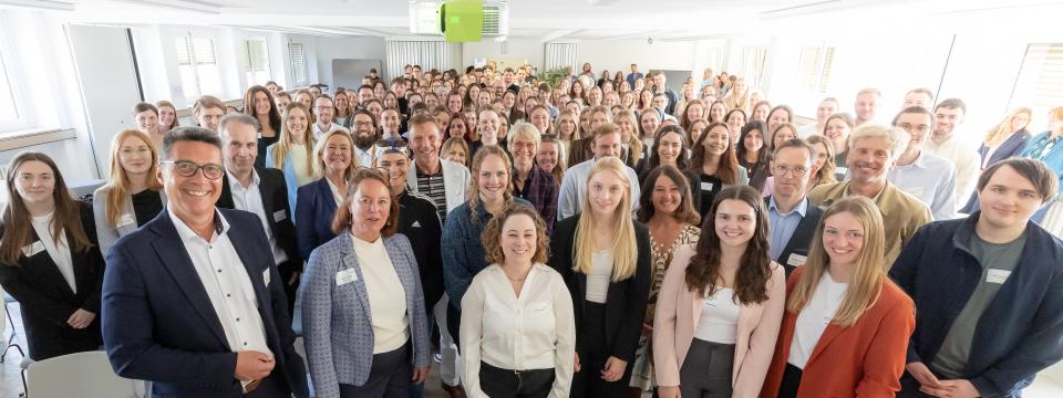 Personen stehen in einem Veranstaltungsraum für ein Gruppenbild zusammen