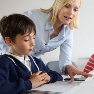 Lehrerin erklärt einem Schüler Unterrichtsstoff mithilfe eines Buches