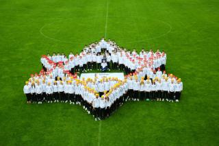 Sportlerinnen und Sportler von MAKKABI e.V. stehen als Davidsstern aufgestellt auf dem Fußballfeld