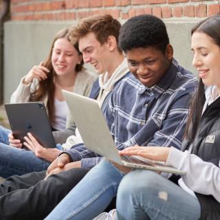 Jugendliche mit Laptops unterhalten sich