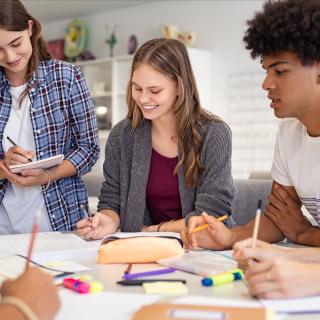 Gruppe von Schülerinnen und Schülern arbeitet gemeinsam an einem Tisch.