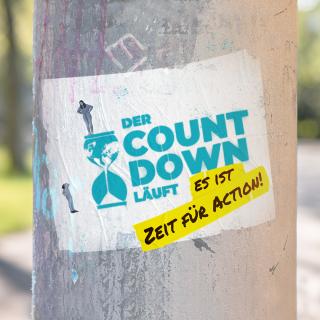 Auf einem Baumstamm sieht man ein Spraybild mit dem Slogan "Der Countdown läuft - es ist Zeit für Action"