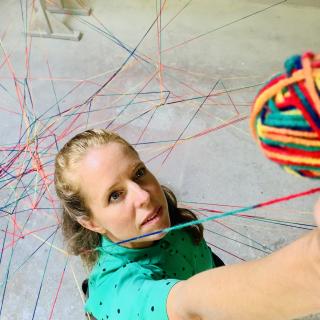 Eine Frau spinnt ein Netzwerk mit bunter Wolle