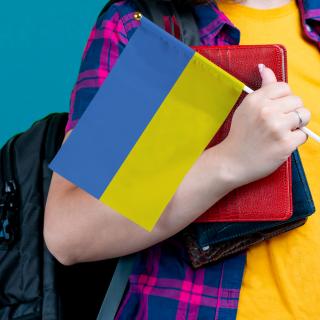 Schülerin mit Rucksack und Ukraine-Flagge