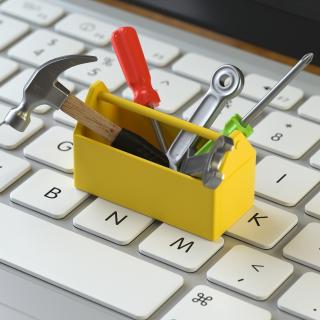Auf einer Computertastatur steht ein Miniatur-Werkzeugkasten.